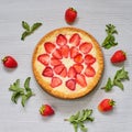 Strawberry tart on the gray kitchen background. Berries cheesecake decorated with organic fresh strawberries and mint Royalty Free Stock Photo