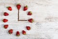 Strawberry time. Strawberry clock with arrows from coffee beans, showing a time of three or fifteen hours on a wooden old board. Royalty Free Stock Photo