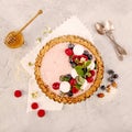 Strawberry vanila tart topped with berries on light gray background