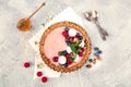 Strawberry vanila tart topped with berries on light gray background