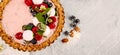 Strawberry vanila tart topped with berries on light gray background