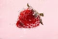 Strawberry in water against pink background, close up Royalty Free Stock Photo