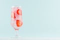 Strawberry water with red fruit slices, ice cubes, sparkling water in misted glass in modern mint color interior.