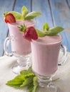 Strawberry yogurt in a glass cup on a blue wooden table.