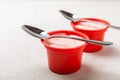 strawberry yogurt in a red plastic cup with a spoon on background.