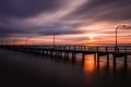 Streaking clouds over a long fishing pier as the sun rises over the horizon. Captree State Park, Long Island NY