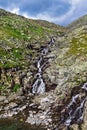 Stream cascades flowing over the rocks in the mountains