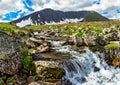 Stream cascades flowing over the rocks in the mountains