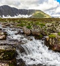 Stream cascades flowing over the rocks in the mountains