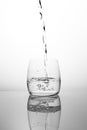 A stream of clean drinking water flows into a transparent glass. Black and white glass with water air bubbles. A bubbling stream Royalty Free Stock Photo