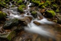 Stream of clear water flowing over mossy boulders Royalty Free Stock Photo