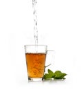 Stream of hot water falling into glass with tea and mint leaves