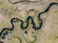 A stream meanders through a green valley, with natural twists and curves. Meandering watercourse Top view. Aerial view