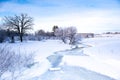 Stream running through a snow covered field with frost on the trees in January, horizontal Royalty Free Stock Photo