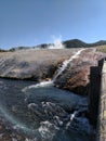 Stream of steaming water flowing into river at Yellowstone National Park