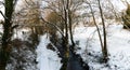 Stream surrounded by trees and roads covered in snow during storm Emma. Royalty Free Stock Photo