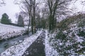 Stream surrounded by trees and roads covered in snow during storm Emma. Royalty Free Stock Photo