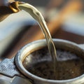 A stream of tea from the spout of the clay kettle flows into the tea strainer