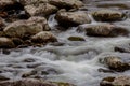 Stream with touches of blue reflections, fall leaves, water flowing over rocks Royalty Free Stock Photo