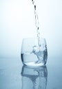 A stream of water flowing into a transparent glass cup with a splash of drops and drops. A jet of clean drinking spring water Royalty Free Stock Photo