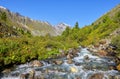 Stream water flows between boulders in mountain tundra