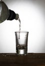 A stream of water flows into a glass from a bottle on an old wooden table as detailed close-up shot, Hand over glass Royalty Free Stock Photo