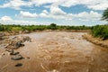 Stream of water in a forest and mountain area, lots of greenery, brown water, contrasting red earth, scorching heat Royalty Free Stock Photo