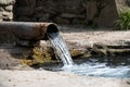 stream of water from a rusty metal pipe flows into a river Royalty Free Stock Photo