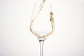 Stream of white wine flows into stem glass, swirls.