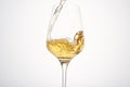 Stream of white wine flows into stem glass, swirls.