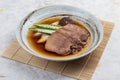 Streamed beef tounge gyutan served with shiitake, Japanese scallion and chilli with soup in rounded stone plate on makisu.