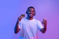 Streaming Music Subscription. Happy black guy in headphones holding smartphone and card