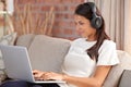 Streaming some music videos. An attractive young woman wearing headphones while using her laptop at home. Royalty Free Stock Photo