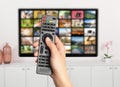 Streaming video services. Woman using remote control to change channels on TV Royalty Free Stock Photo