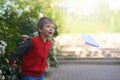 Streat portrait of the preschool boy launching a paper plane