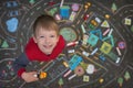 Streat portrait of the preschool boy playing cars in the chalk drawn city