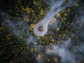 Street from above trough a misty forest at autumn, aerial view flying through the clouds with fog and trees Royalty Free Stock Photo