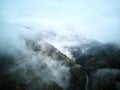 Street from above trough a misty forest at autumn, aerial view flying through the clouds with fog and trees Royalty Free Stock Photo