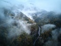 Street from above trough a misty forest at autumn, aerial view flying through the clouds with fog and trees Royalty Free Stock Photo