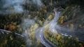 Street from above trough a misty forest at autumn, aerial view flying through the clouds with fog and trees Royalty Free Stock Photo