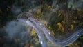 Street from above trough a misty forest at autumn, aerial view flying through the clouds with fog and trees Royalty Free Stock Photo