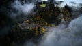 Street from above trough a misty forest at autumn, aerial view flying through the clouds with fog and trees Royalty Free Stock Photo