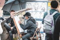 Street artist drawing portrait of a tourists on Charles bridge in Prague