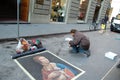 Street artist draws on the asphalt portrait of a lady with an ermine.