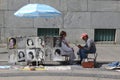 Street artist making a sketch or a portrait to a woman sitting on a chair