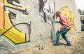 Street artist painting colorful graffiti art on generic wall