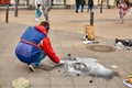 A street artist paints a realistic portrait on the floor of a city square. Street art