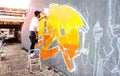 Street artist working on colored graffiti at public space wall - Modern art perform concept of urban guy painting live murales Royalty Free Stock Photo