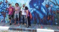 Street artists gathered around their blue mural about a woman and nature