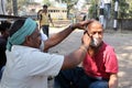 Street barber shaving a man on a street in Kolkata